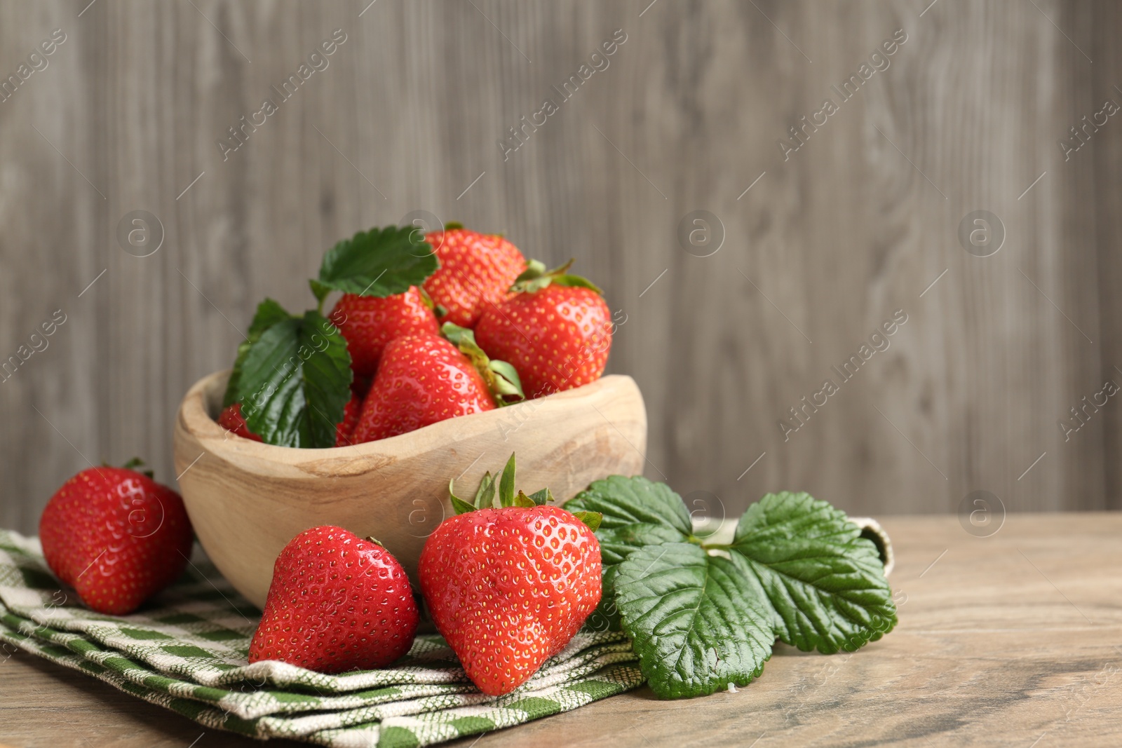 Delicious ripe strawberries and green leaves on wooden table, closeup. Space for text Photo of Delicious ripe strawberries and green leaves on wooden table, closeup. Space for text