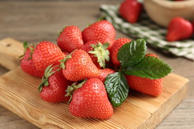 Photo of Delicious ripe strawberries and green leaves on table, closeup