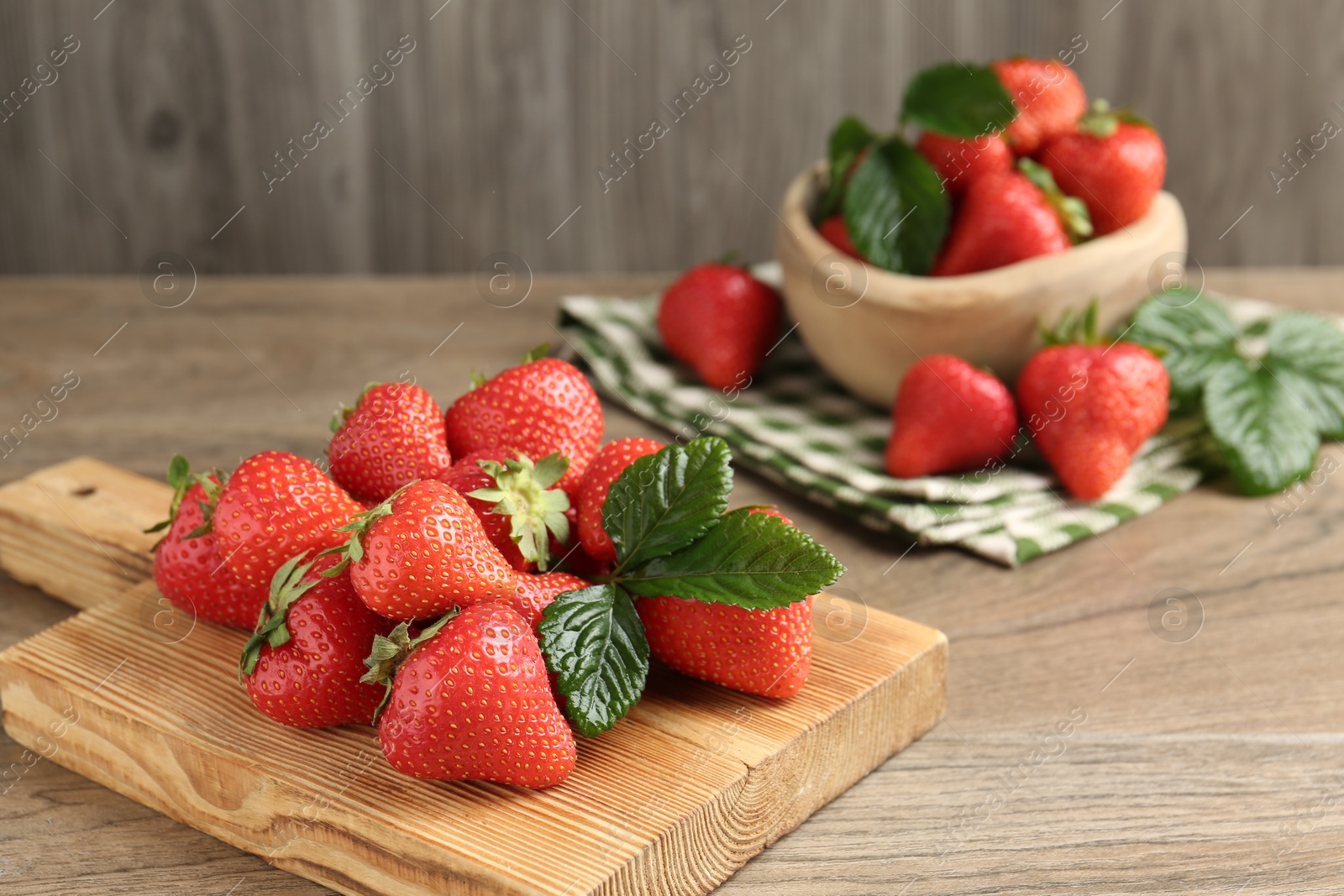 Delicious ripe strawberries and green leaves on wooden table, closeup. Space for text Photo of Delicious ripe strawberries and green leaves on wooden table, closeup. Space for text