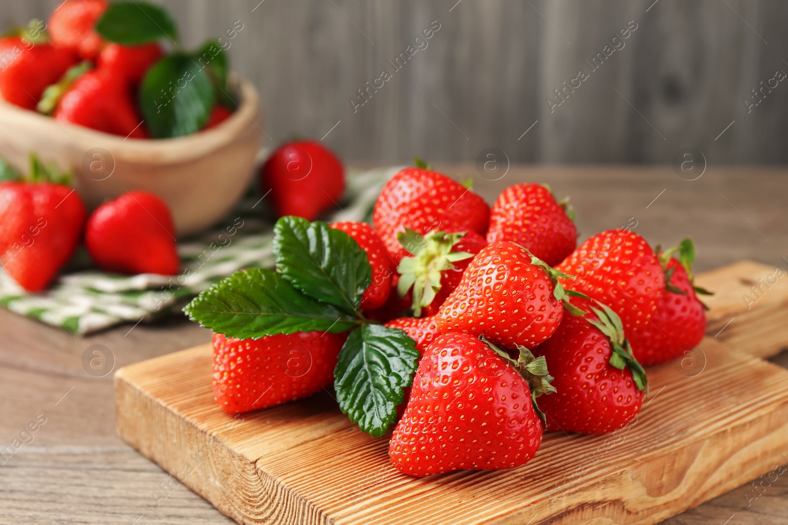 Delicious ripe strawberries and green leaves on wooden table, closeup Photo of Delicious ripe strawberries and green leaves on wooden table, closeup