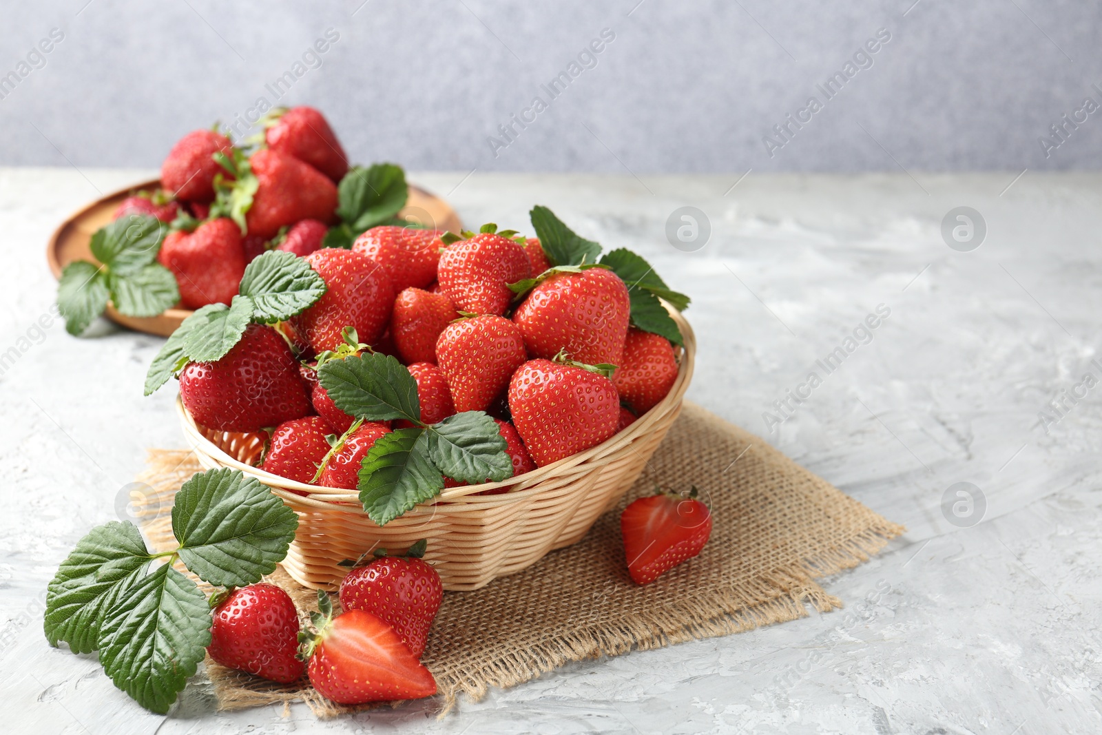 Delicious ripe strawberries and green leaves on grey table, closeup. Space for text Photo of Delicious ripe strawberries and green leaves on grey table, closeup. Space for text