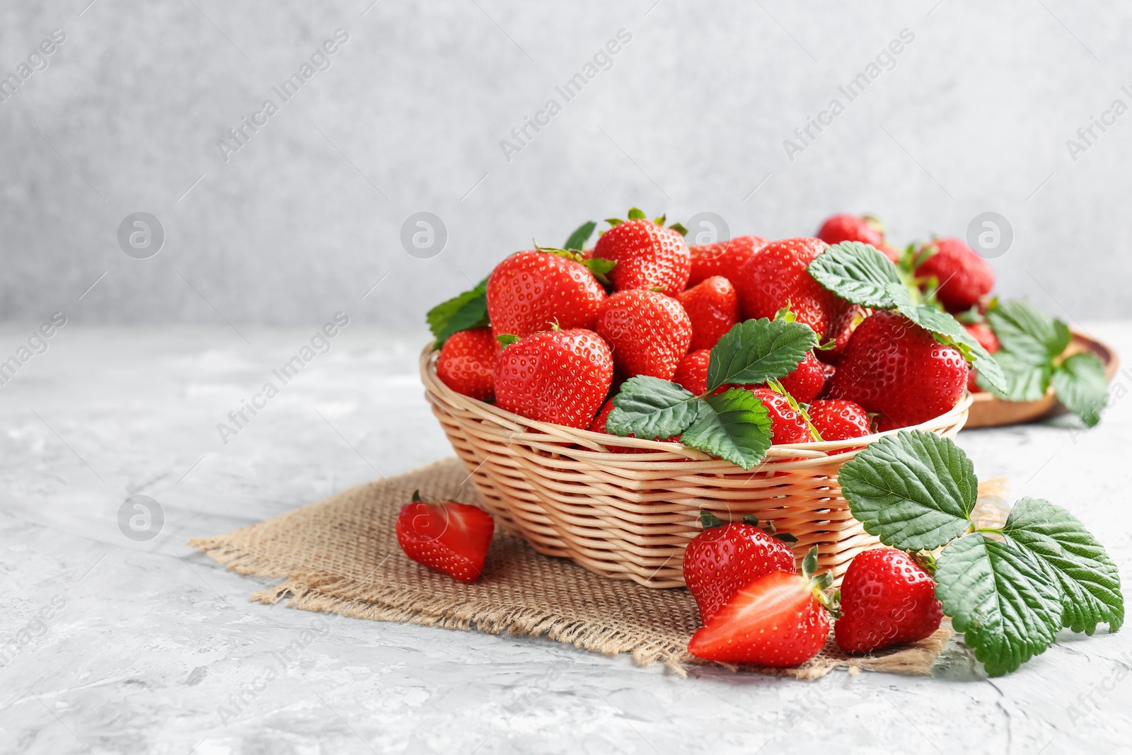 Delicious ripe strawberries and green leaves on grey table, closeup. Space for text Photo of Delicious ripe strawberries and green leaves on grey table, closeup. Space for text