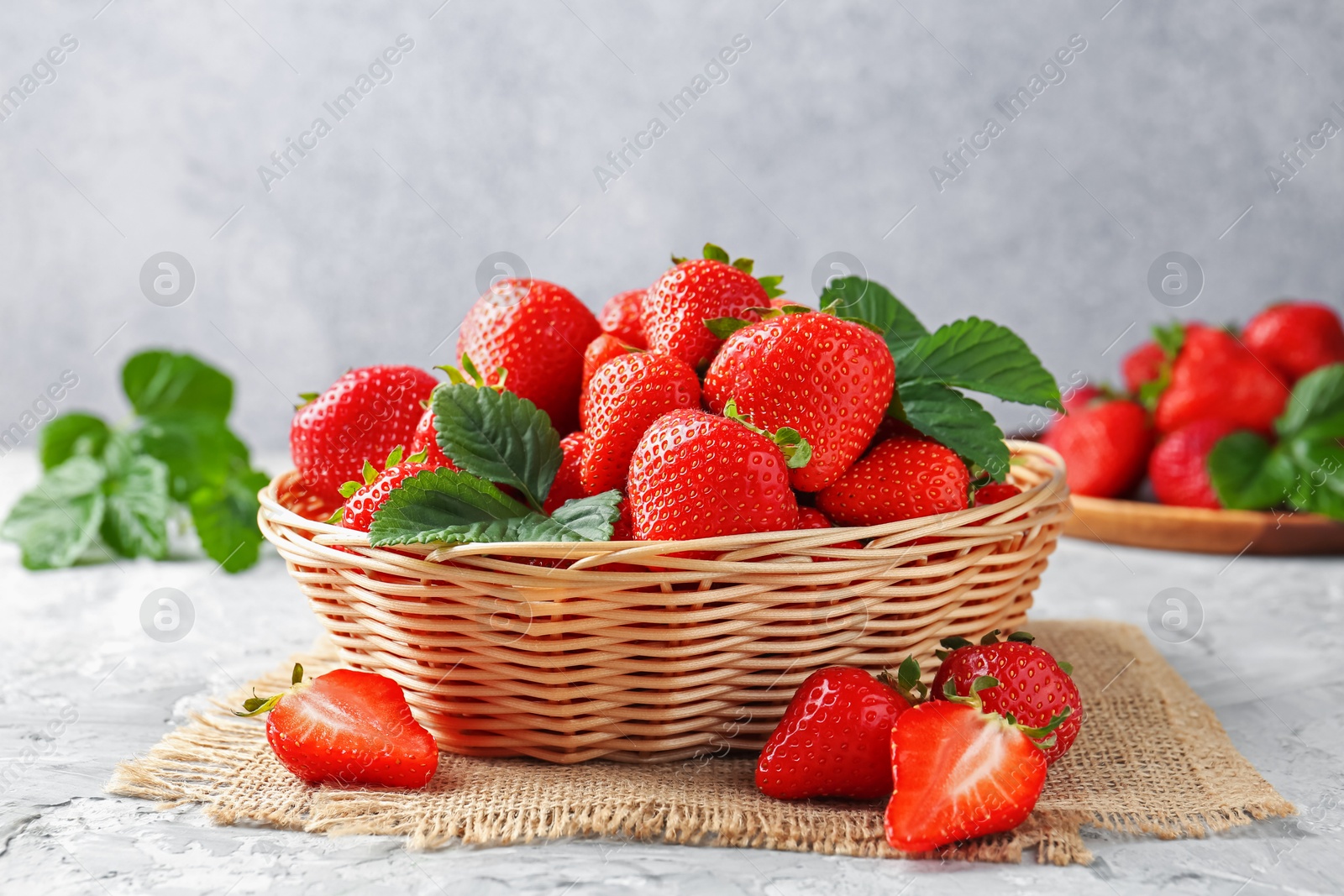 Delicious ripe strawberries and green leaves on grey table, closeup Photo of Delicious ripe strawberries and green leaves on grey table, closeup