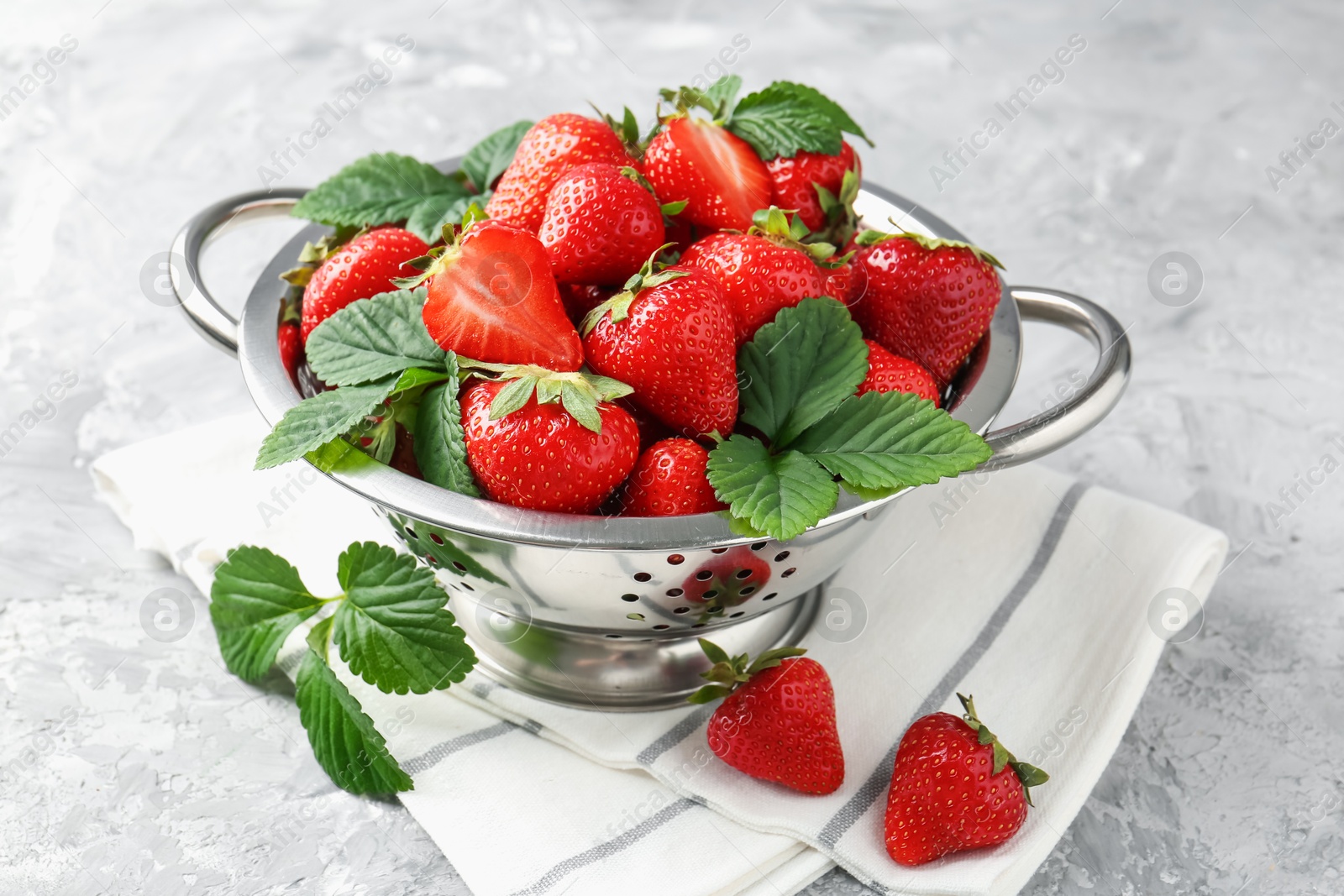 Delicious ripe strawberries and green leaves on grey table, closeup Photo of Delicious ripe strawberries and green leaves on grey table, closeup
