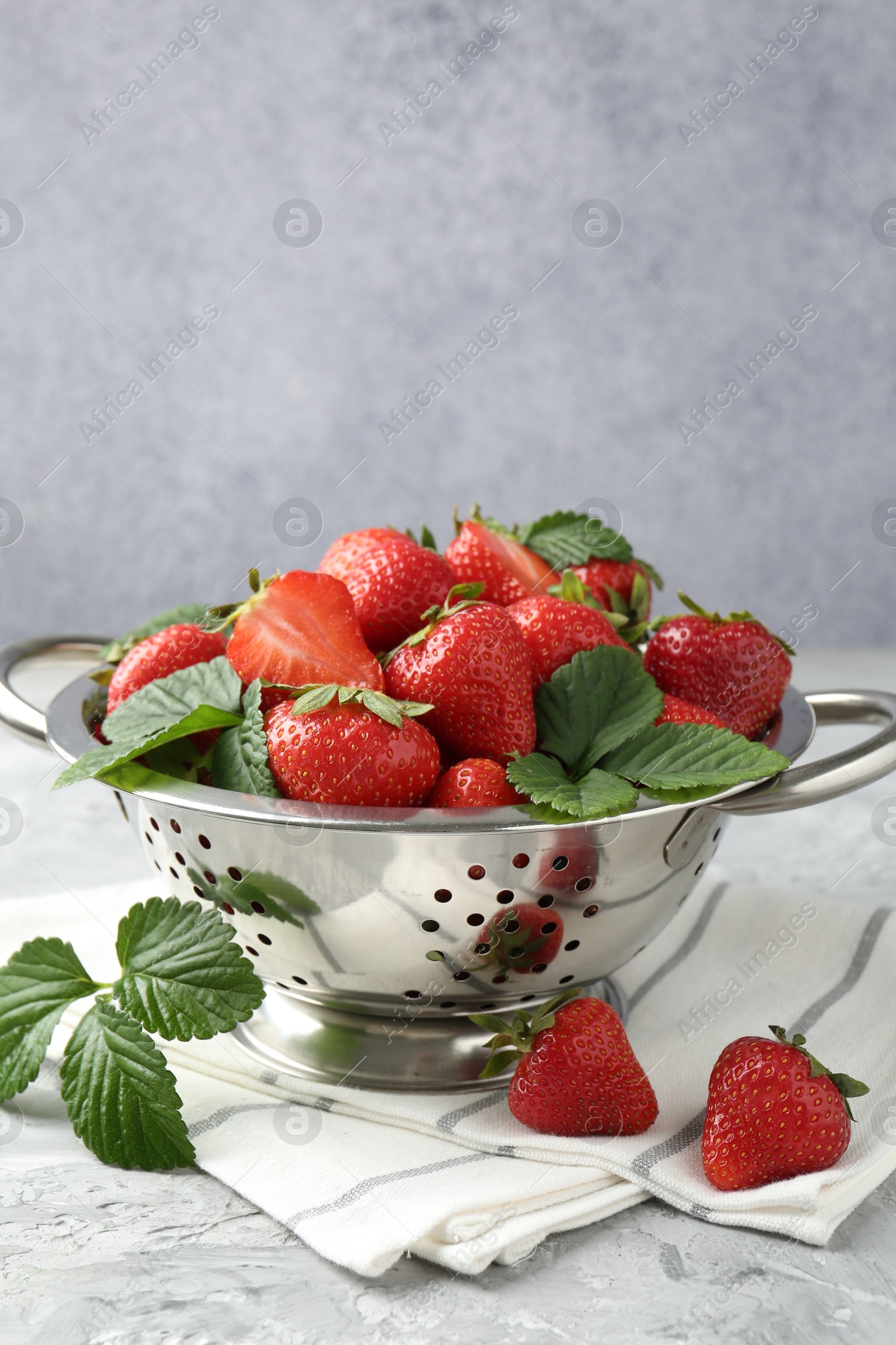 Delicious ripe strawberries and green leaves on grey table, closeup Photo of Delicious ripe strawberries and green leaves on grey table, closeup
