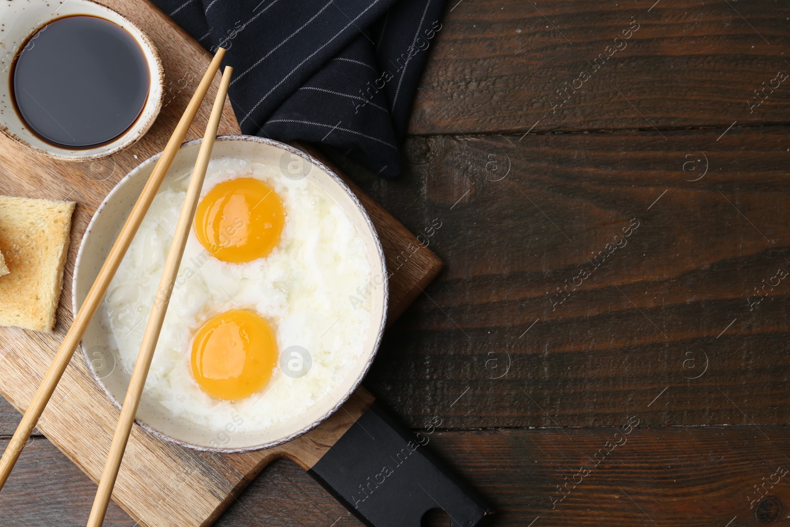 Traditional asian breakfast with half-boiled eggs in bowl, soy sauce, bread and chopsticks on wooden table, top view. Space for text Photo of Traditional asian breakfast with half-boiled eggs in bowl, soy sauce, bread and chopsticks on wooden table, top view. Space for text