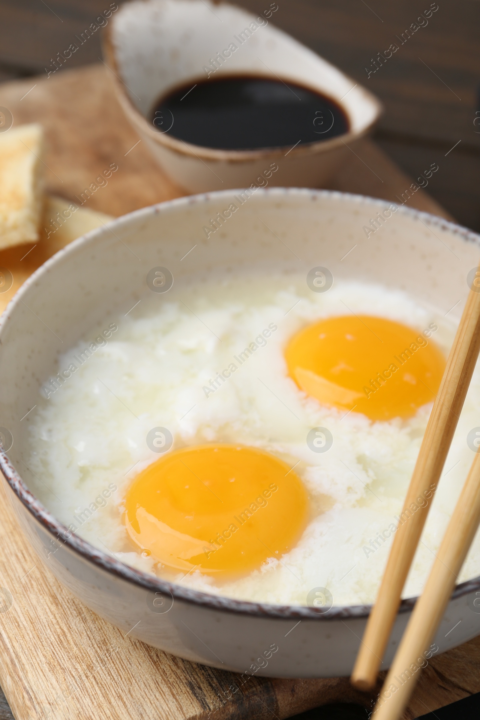 Traditional asian breakfast with half-boiled eggs in bowl, chopsticks and soy sauce on table, closeup Photo of Traditional asian breakfast with half-boiled eggs in bowl, chopsticks and soy sauce on table, closeup