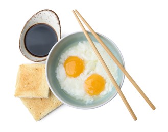 Photo of Half-boiled eggs in bowl, soy sauce, toasts and chopsticks isolated on white, top view. Traditional asian breakfast