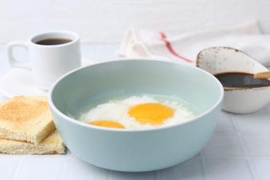 Photo of Traditional asian breakfast with half-boiled eggs in bowl, soy sauce, bread and coffee on white tiled table, closeup