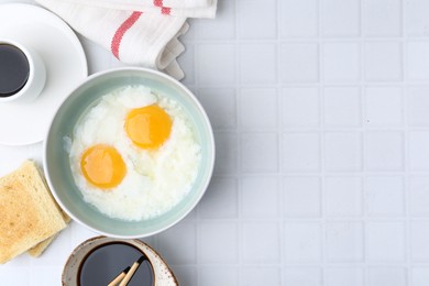 Photo of Traditional asian breakfast with half-boiled eggs in bowl, soy sauce, toast and coffee on white tiled table, flat lay. Space for text