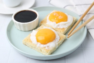 Photo of Tasty kaya toasts with half-boiled eggs served on white tiled table, closeup. Traditional asian breakfast