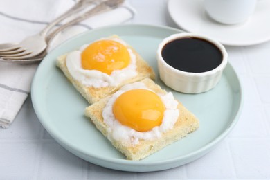 Photo of Tasty kaya toasts with half-boiled eggs served on white tiled table, closeup. Traditional asian breakfast
