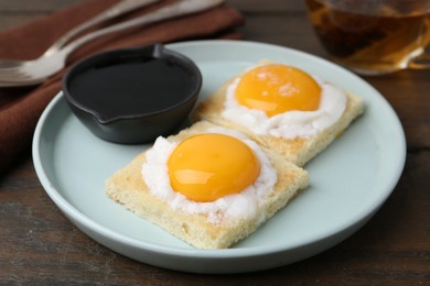 Photo of Tasty kaya toasts with half-boiled eggs served on wooden table, closeup. Traditional asian breakfast