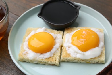 Photo of Tasty kaya toasts with half-boiled eggs served on wooden table, closeup. Traditional asian breakfast