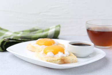 Photo of Tasty kaya toasts with half-boiled eggs served on light grey table, closeup. Traditional asian breakfast