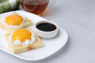 Photo of Traditional asian breakfast with tasty kaya toasts and half-boiled eggs served on light grey table, closeup. Space for text