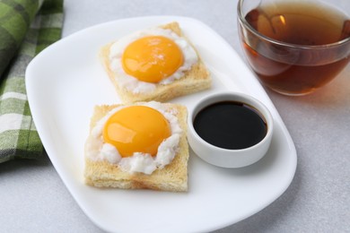 Photo of Tasty kaya toasts with half-boiled eggs served on light grey table, closeup. Traditional asian breakfast