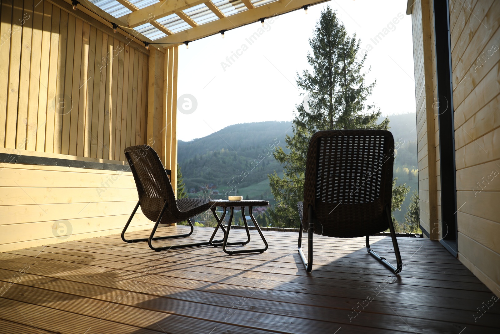 Beautiful terrace with wicker armchairs and table in mountains Photo of Beautiful terrace with wicker armchairs and table in mountains