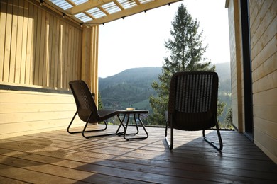 Photo of Beautiful terrace with wicker armchairs and table in mountains