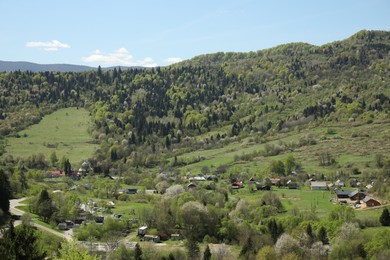Photo of Picturesque view of mountains, village and forest on sunny day