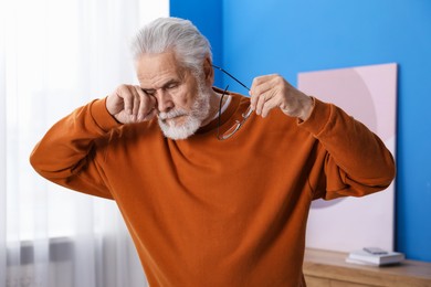 Photo of Senior man with glasses suffering from eyestrain at home