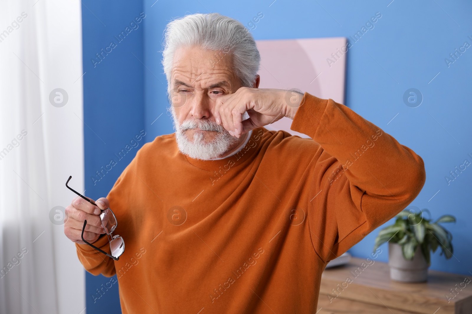 Senior man with glasses suffering from eyestrain at home Photo of Senior man with glasses suffering from eyestrain at home