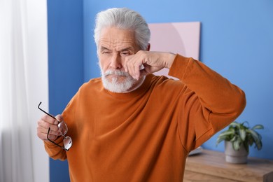 Photo of Senior man with glasses suffering from eyestrain at home