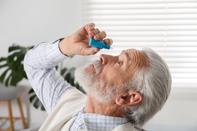 Photo of Senior man applying eye drops at home