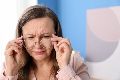 Photo of Woman with glasses suffering from eyestrain at home, space for text