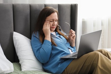 Photo of Woman with vision problem using laptop on bed at home