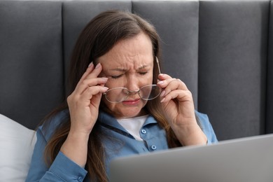 Photo of Woman with vision problem using laptop on bed at home
