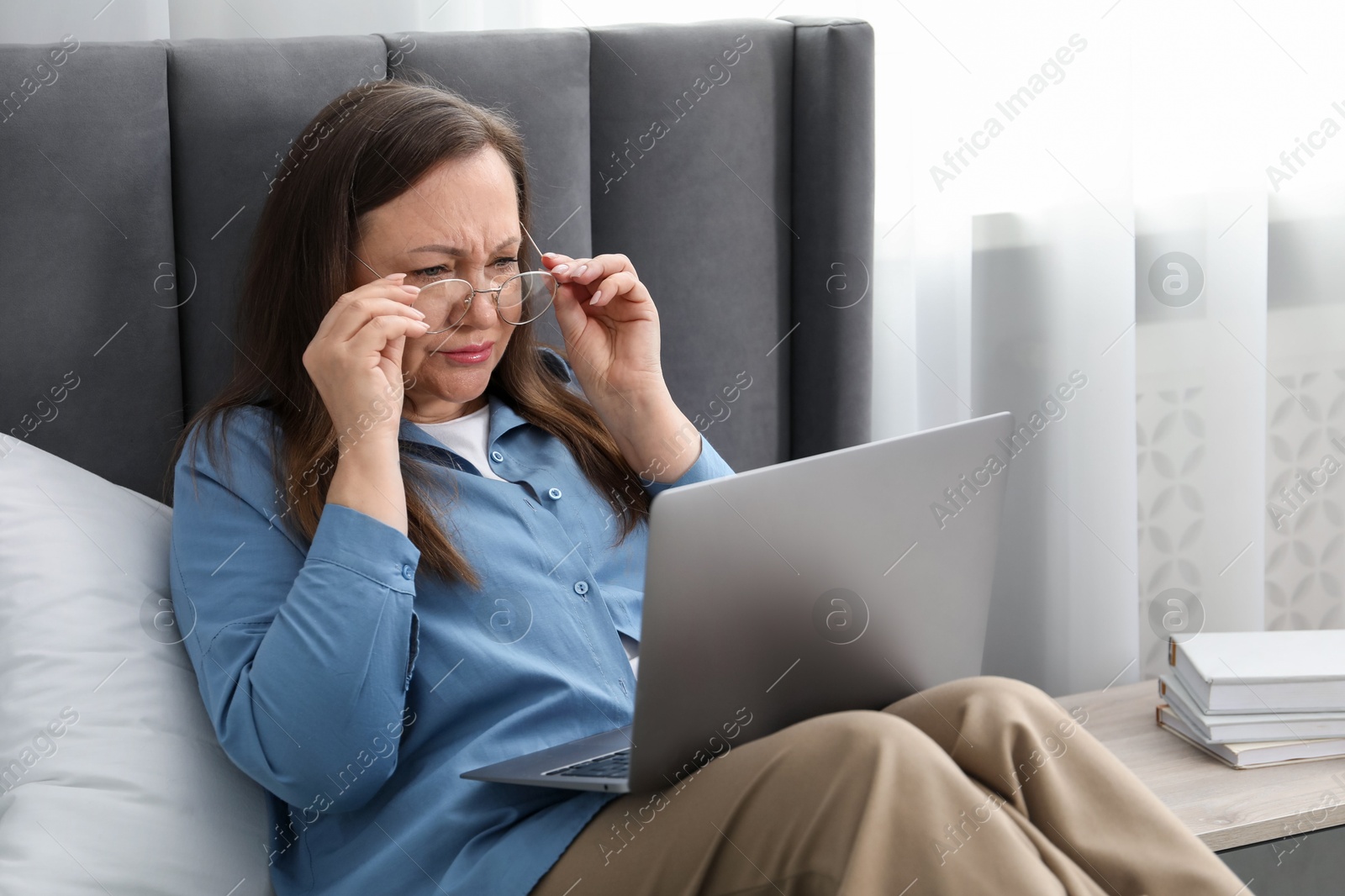 Woman with vision problem using laptop on bed at home Photo of Woman with vision problem using laptop on bed at home