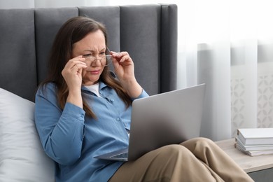 Photo of Woman with vision problem using laptop on bed at home