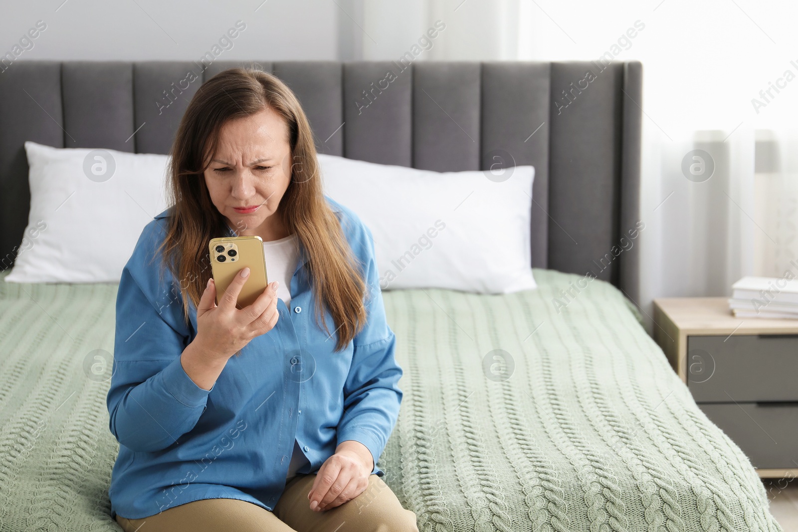Woman with vision problem using smartphone on bed at home, space for text Photo of Woman with vision problem using smartphone on bed at home, space for text