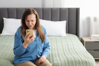 Photo of Woman with vision problem using smartphone on bed at home, space for text