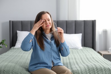Photo of Woman with glasses suffering from eyestrain on bed at home, space for text