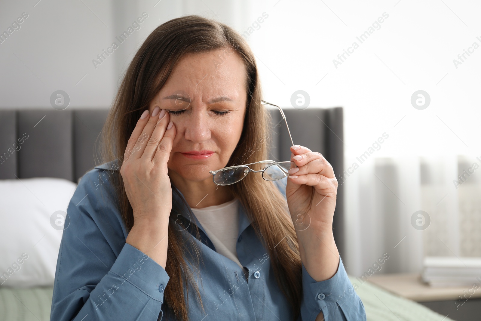 Woman with glasses suffering from eyestrain on bed at home Photo of Woman with glasses suffering from eyestrain on bed at home
