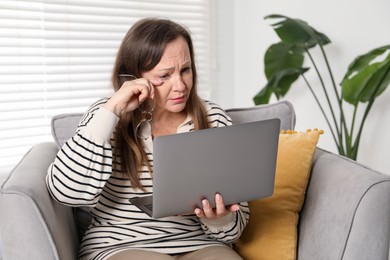 Photo of Woman with vision problem using laptop in armchair at home