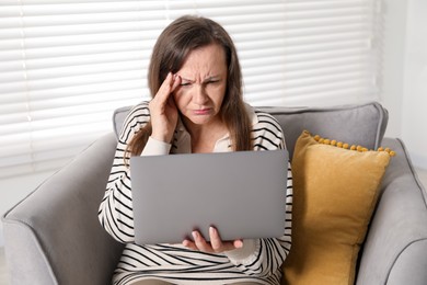 Photo of Woman with vision problem using laptop in armchair at home