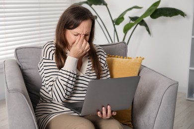 Photo of Woman with vision problem using laptop in armchair at home