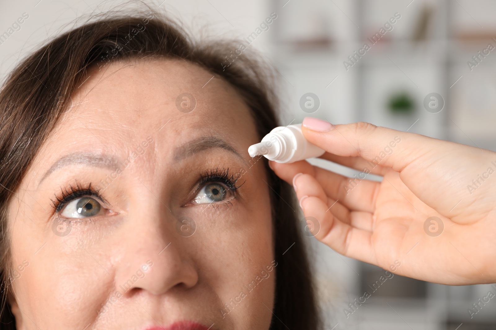 Daughter dripping medication into mother's eye at home, closeup Photo of Daughter dripping medication into mother's eye at home, closeup