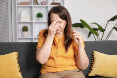 Photo of Woman with glasses suffering from eyestrain on sofa at home