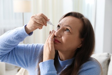 Photo of Woman applying eye drops on sofa at home