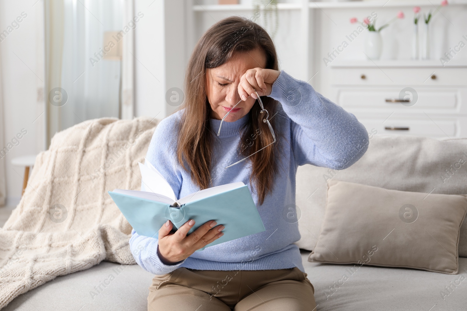 Woman with vision problem reading book on sofa at home Photo of Woman with vision problem reading book on sofa at home