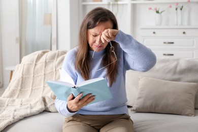 Photo of Woman with vision problem reading book on sofa at home