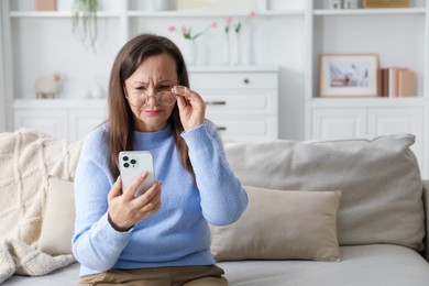 Photo of Woman with vision problem using smartphone on sofa at home