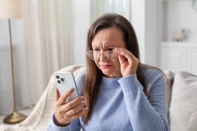 Photo of Woman with vision problem using smartphone on sofa at home