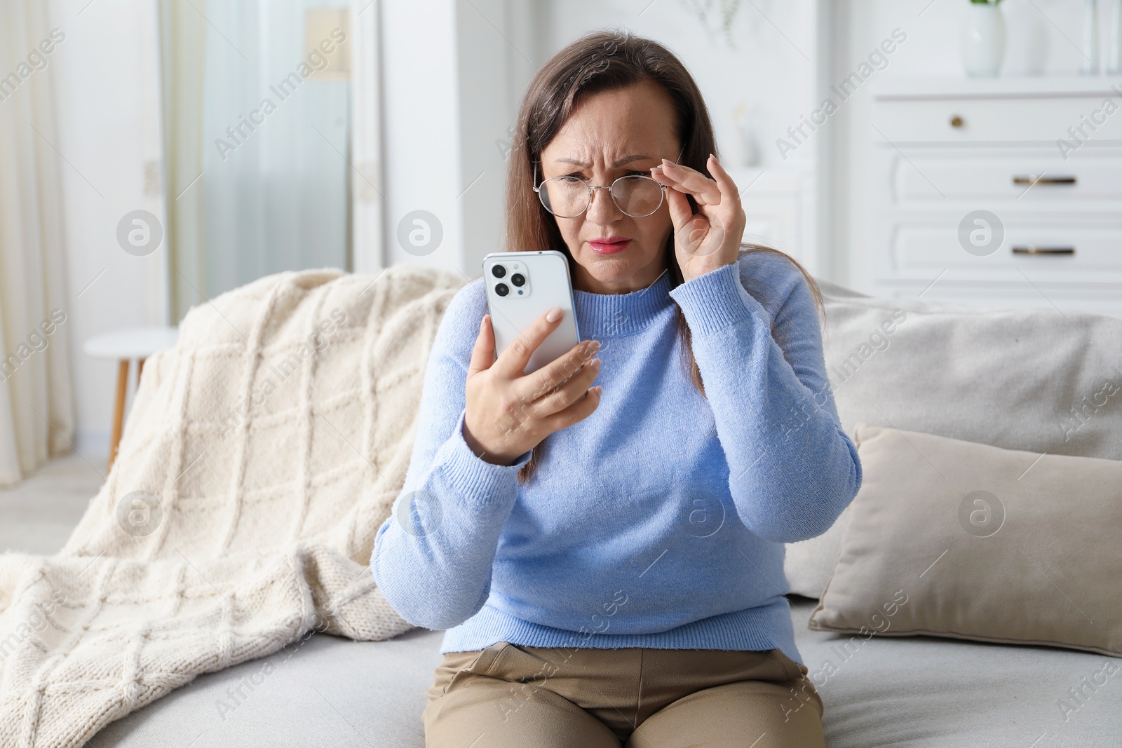 Woman with vision problem using smartphone on sofa at home Photo of Woman with vision problem using smartphone on sofa at home