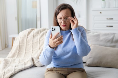 Photo of Woman with vision problem using smartphone on sofa at home