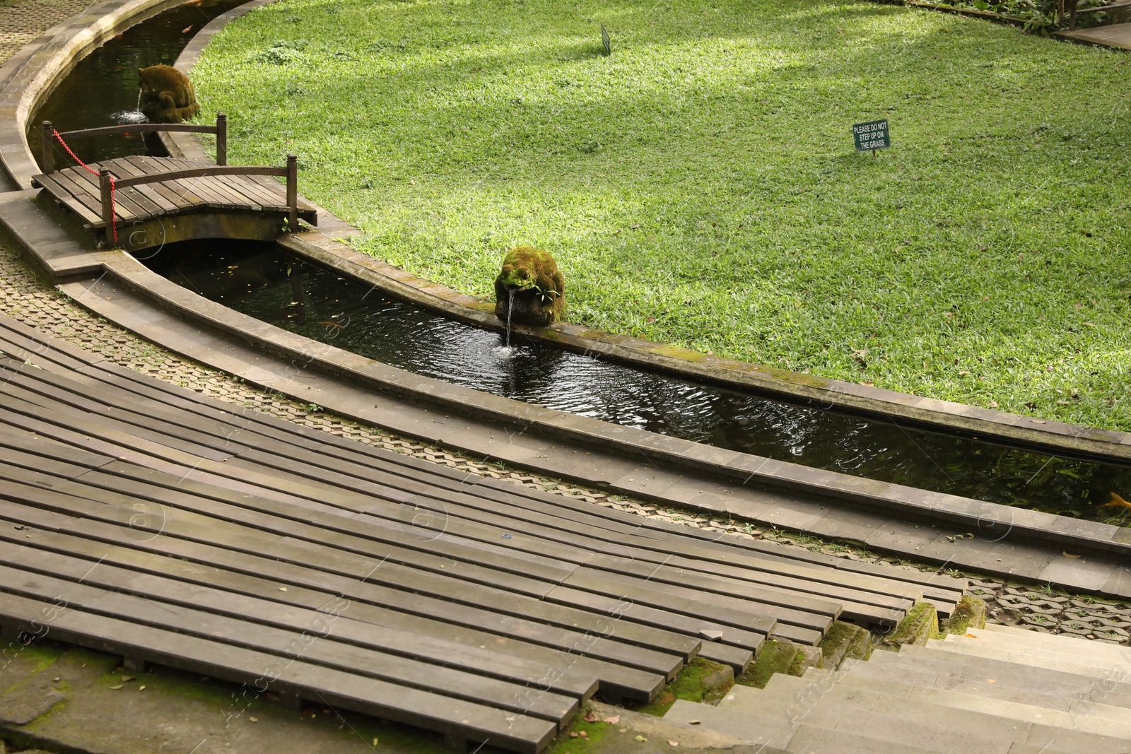 Wooden benches, water canal and green lawn outdoors Photo of Wooden benches, water canal and green lawn outdoors